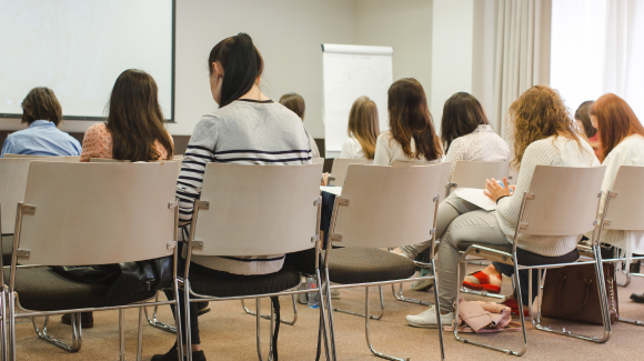 Eine Schulklasse sitzt auf Stühlen und hört sich einen Vortrag an. - demphoto | stock.adobe.com