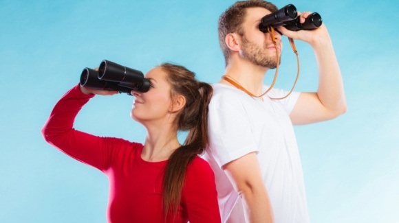 weibliche und männliche junge Erwachsene blicken durch Ferngläser