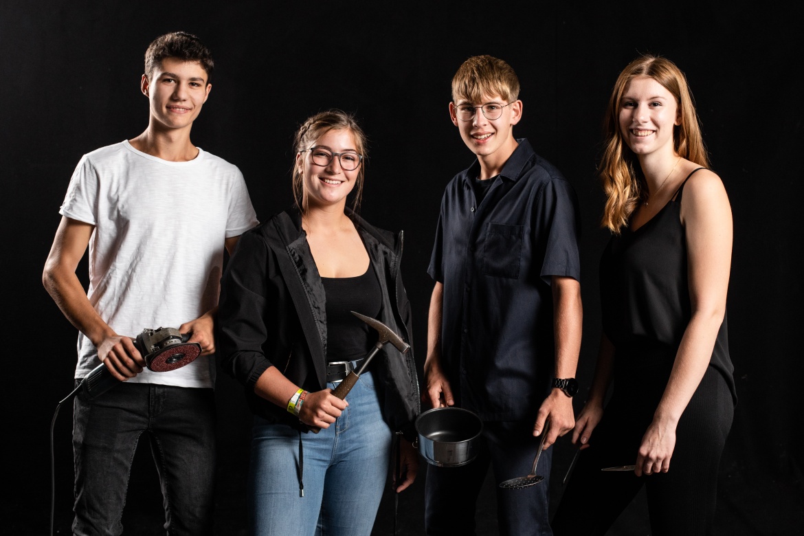 Gruppe von Lehrlingen mit einem Arbeitsgerät in der Hand.